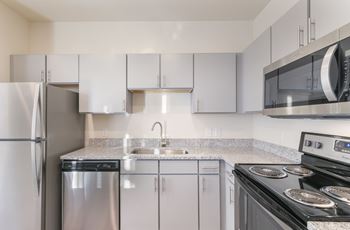 A kitchen with a stove, refrigerator, and microwave.